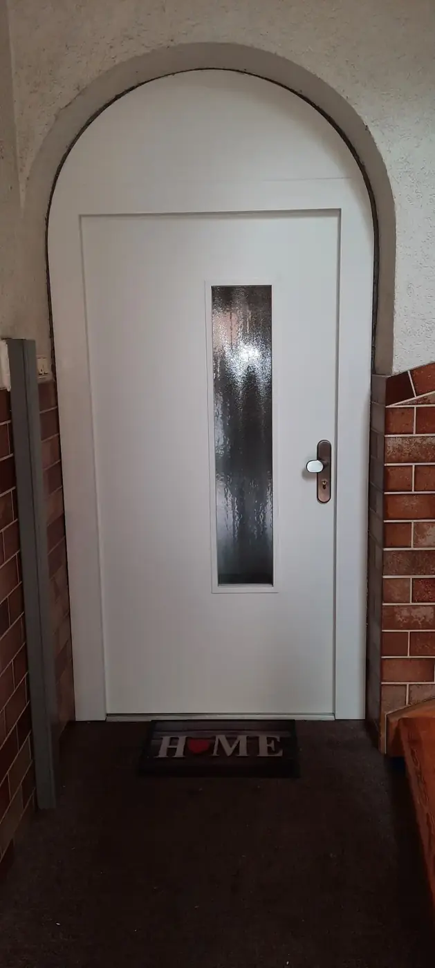 Weiße Haustür mit Glaseinsatz in einem Rundbogen